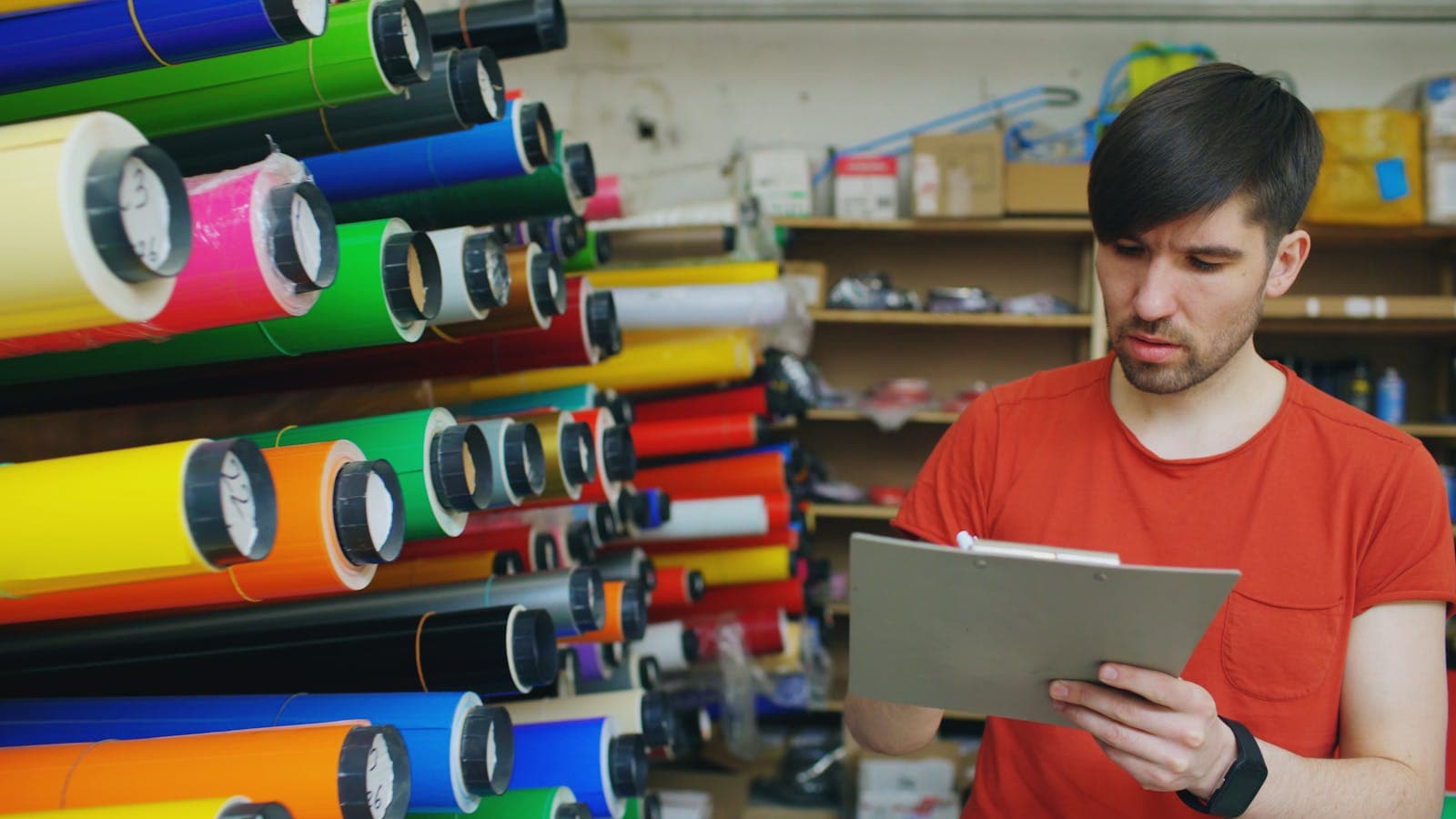 Workshop owner in a red t-shirt reviewing a checklist in his own premises